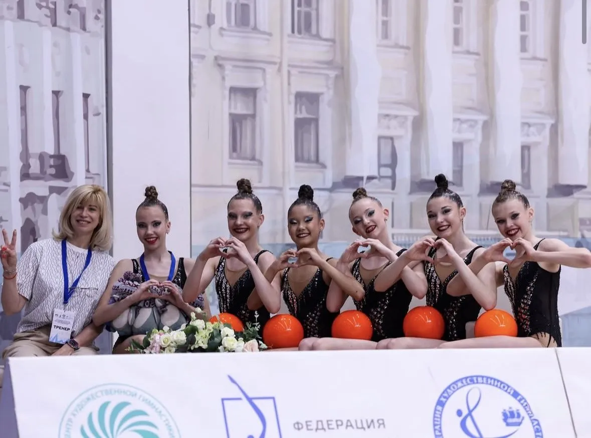 Команда гимнасток и тренер после выступления с мячами